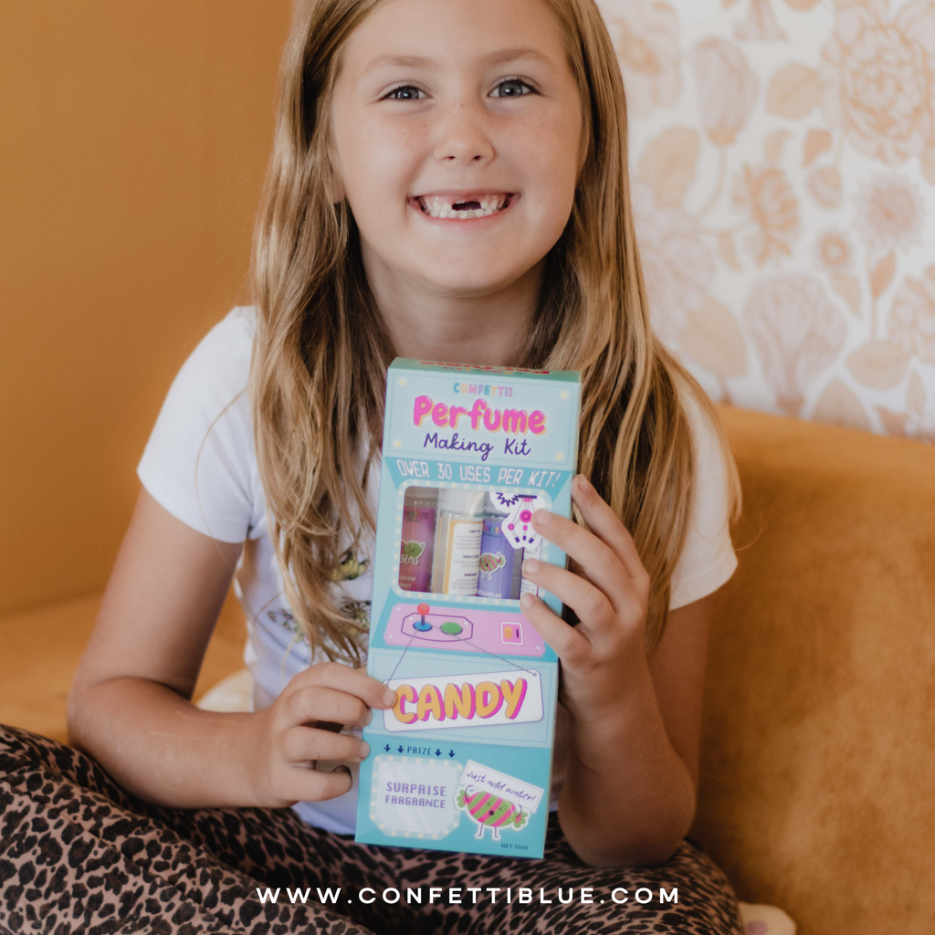 7 year old Girl with white shirt holding a Confetti Blue Candy Scented Perfume Making Kit for Kids. 